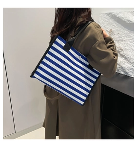 Detail of blue and white striped canvas tote bag showing side profile and shoulder strap