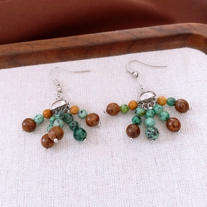 Détail macro de boucles d'oreilles ethniques en perles de bois et verre avec pompons