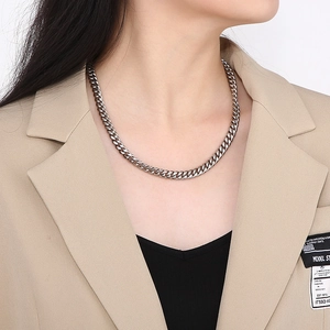 Polished silver Cuban link chain necklace worn by a model in a beige blazer suit
