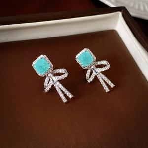 Detail of flower earrings with square green stone and pavé crystal bow design