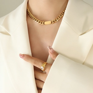 Detail of a gold Cuban link necklace and a bold gold ring set with a clear zircon stone