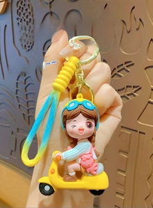 Detailed view of cartoon girl on yellow electric scooter keychain with gradient strap