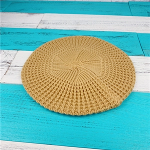 Nahaufnahme einer gelben Strickbaske mit Waffelstruktur auf blauem Holzuntergrund