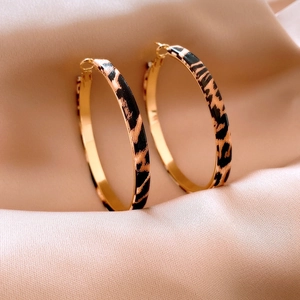 Detail of leopard print hoop earrings with golden inner finish on pink silk fabric