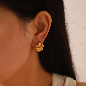 Gros plan détaillé d'un clip d'oreille en forme de coquille dorée porté sur le lobe