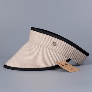Detail of beige linen sun visor featuring black trim and a gold metal logo button