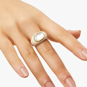 Close-up of a minimalist gold-plated ring featuring a white oval shell inlay on hand