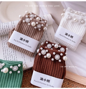 Detailed view of ribbed knit socks with elegant pearl and rhinestone flower embellishments