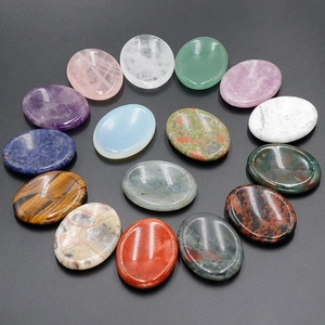 Oval natural crystal and gemstone massage stones in various colors on a grey background