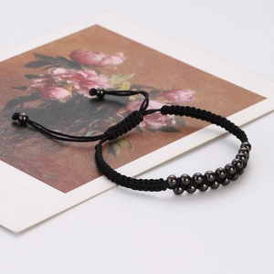 Detail of a double-row black metal bead braided bracelet with an adjustable sliding cord