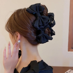 Vue latérale de la grande pince à cheveux à nœud en mousseline noire sur un chignon