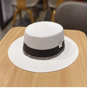 Dettaglio cappello di paglia bianco con nastro nero e fibbia a fiore in metallo argento
