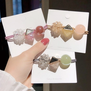 Close-up of three beaded hair ties with resin accents on a display card for girls