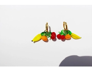 Detailed macro view of creative fruit-shaped earrings with colorful charms and gold hooks