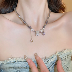 Detail of beaded necklace with purple crystal bear pendant and heart charm on a model