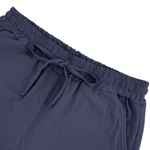 Detail of dark blue linen shorts featuring elastic waistband and drawstring texture