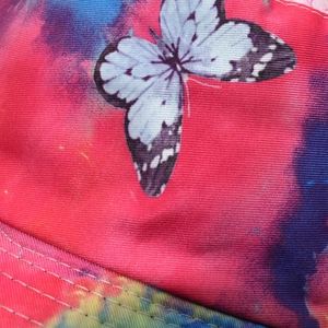 Macro detail of tie-dye fabric with butterfly print and reinforced stitching on a bucket hat