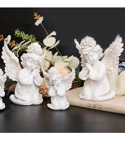 Macro detail of three white resin cherub angel statues in prayer pose on books
