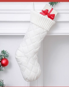 Close-up of white knit Christmas stocking with textured cable pattern on a fireplace mantel