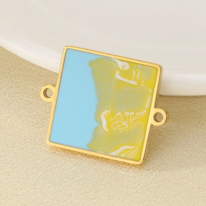 Macro view of a square gold-framed enamel charm with blue and yellow sunset island colors