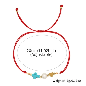 Detailed view of red woven bracelet with turquoise cross pearl and heart charms