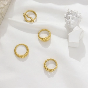 Collection of four gold-plated stainless steel rings with twist and braided designs
