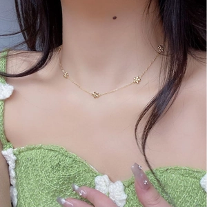 Detail of 925 sterling silver daisy necklace in gold finish worn by model on green fabric