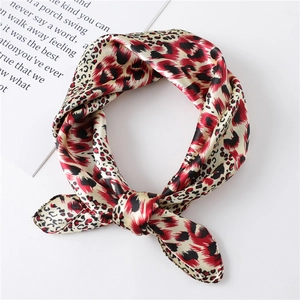 Detail shot of a red leopard print satin silk square scarf tied in a stylish knot