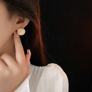 Close-up of a model wearing vintage round cat eye stone earrings with gold metal edges