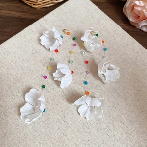 Détails des boucles d'oreilles fleurs en tissu blanc avec perles colorées et franges