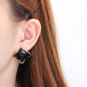 Detail of elegant black and gold irregular square earrings worn on a model's ear