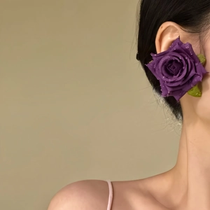 Detailed macro view of an elegant purple fabric rose earring with realistic water droplets.