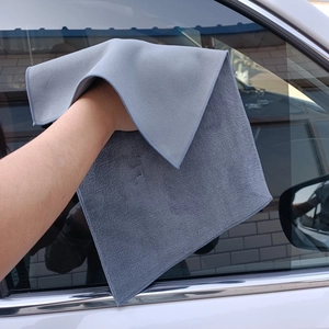 Gray microfiber car cleaning cloth wiping a window for professional auto detailing