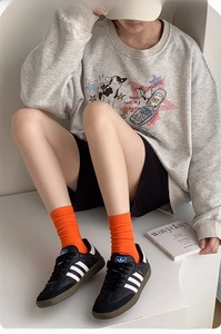 Vibrant orange ribbed crew socks paired with black sneakers and casual loungewear