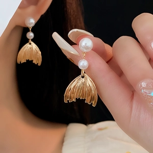 Detail of gold fishtail earrings with white pearls shown on a model for elegant look