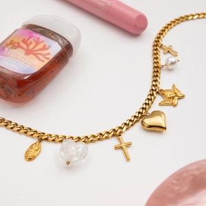 Gold layered curb chain bracelet featuring heart and cross charms on white background
