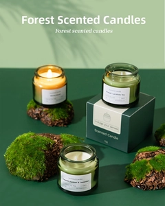 Detailed view of soy wax candles in glass jars with gift packaging and forest decor