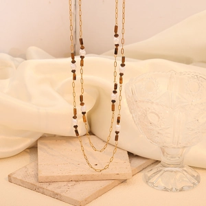 Detailed view of a double-layered golden chain with tiger eye beads and white pearls