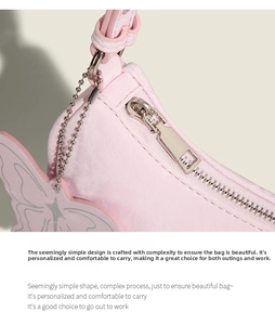 Close-up of a light pink underarm bag featuring silver zipper and butterfly bead charm