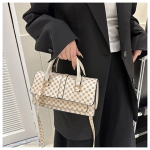 Detail view of cream-colored handbag featuring brown geometric patterns and golden metal hardware
