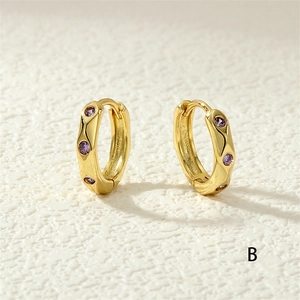 Macro view of gold plated hoop earrings with purple cubic zirconia stones
