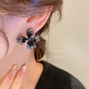 Vue macro de boucles d'oreilles fleur en cristal avec pierres sombres sur l'oreille