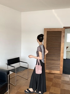 Chic pink hollow woven bucket bag paired with a minimalist black outfit in a studio