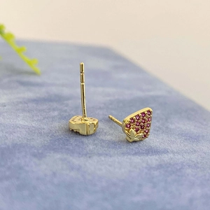 Macro detail of strawberry stud earrings with red pavé stones and 18k gold plating