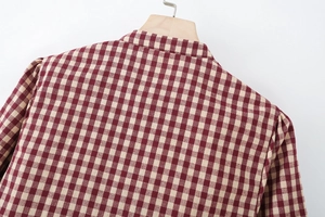 Detailaufnahme eines rot-weiß karierten Hemdrückens mit Stofftextur auf einem Holzbügel