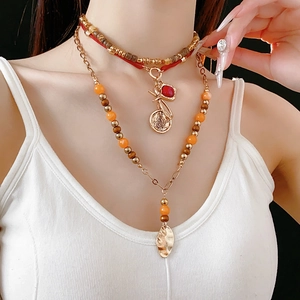Close-up of double-layer beaded necklace with wooden beads, key and leaf pendants