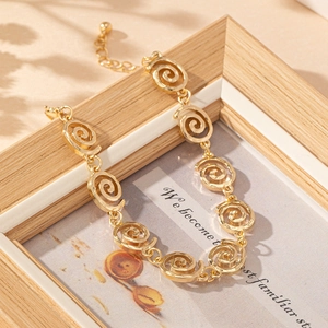 Close-up of golden spiral link bracelet with lobster clasp on elegant artistic background