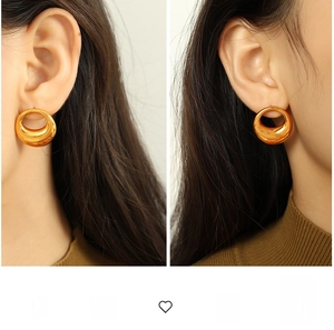 Detailed view of exaggerated large hollow gold hoop earrings with polished metal finish