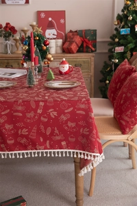 Detailed view of red Christmas tablecloth with gold festive patterns and white tassels