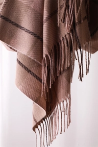 Close-up of brown plaid cashmere-like scarf showing soft texture and tassel fringe details